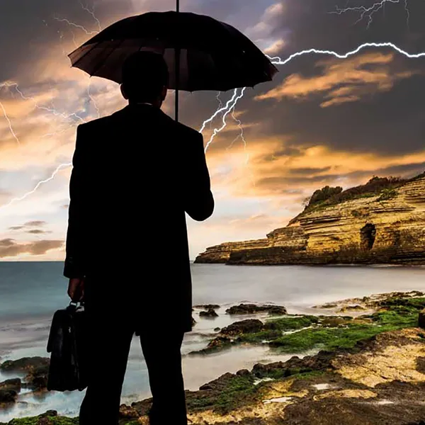The silhouette of a person holding an umbrella with a lightning strike in the background.