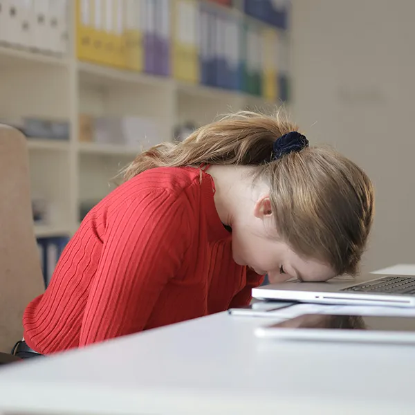 A woman resting her forehead on her laptop keyboard.