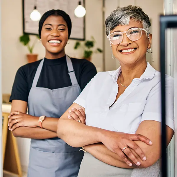 A pair of smiling women standing in the doorway of their business.