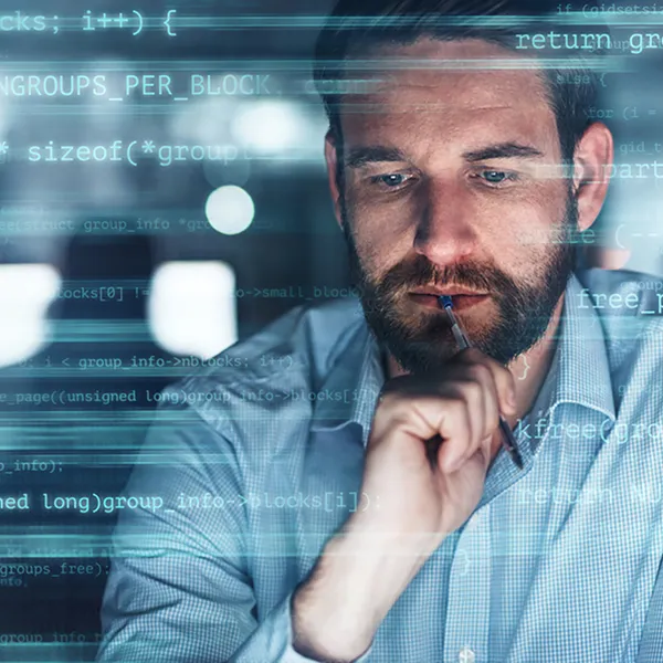 A professional holding a pen surrounded by lines of code.