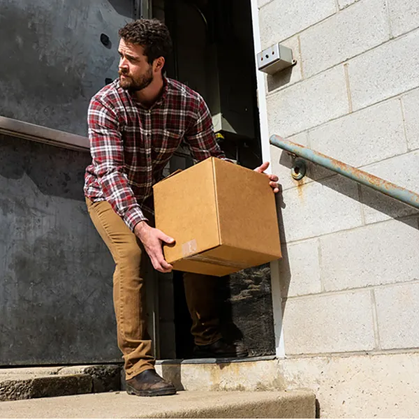 A man picking a package up off of a set of concrete steps.