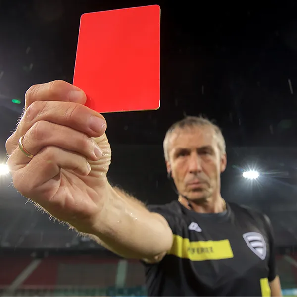 A referee at a soccer match holding a red card.