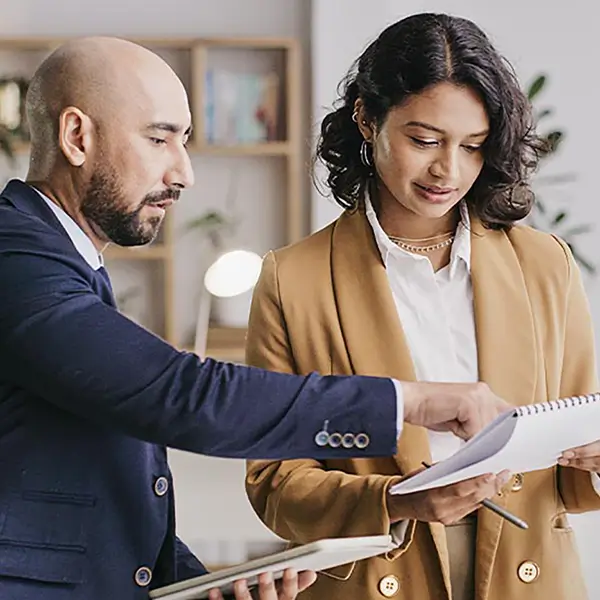 A pair of professionals reviewing information in a notebook.