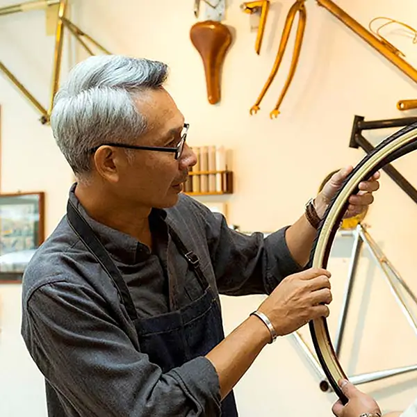 A bike shop employee and a customer looking at a bicycle tire.