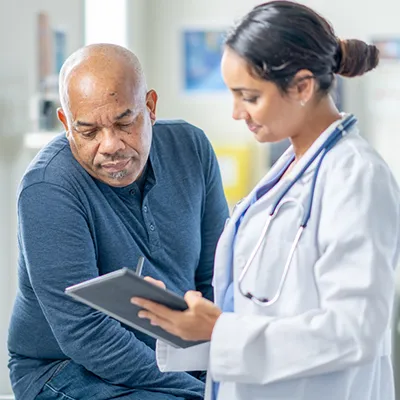 A doctor and patient looking over a tablet while in an examination room.
