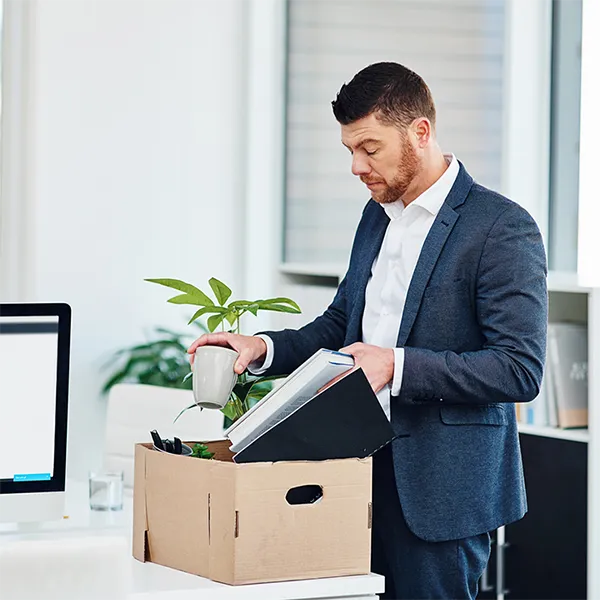 A businessman packing his desk up in a cardboard box.