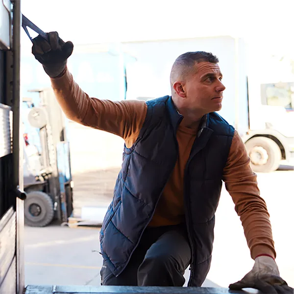 A transportation worker closing the back of a truck.