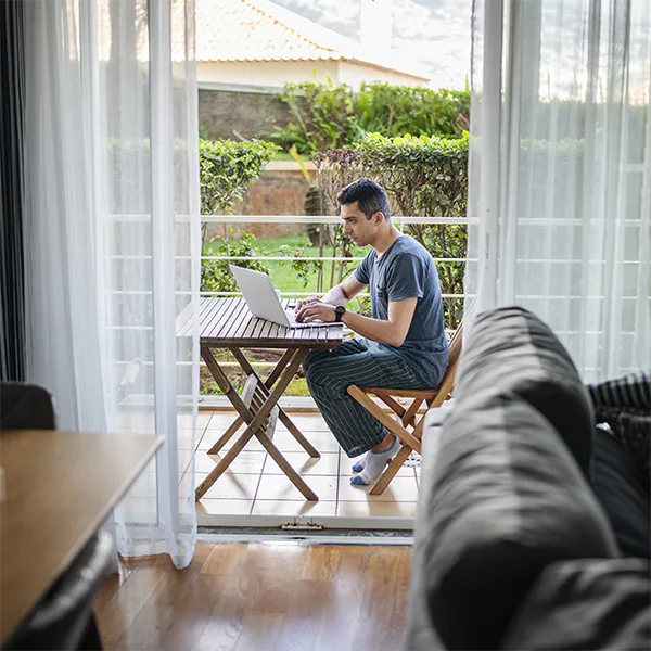 A person typing on their laptop while working on their patio.