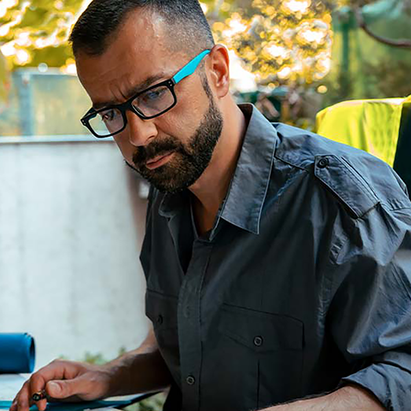 A contractor looking seriously at a table with blueprints, a calculator, and other tools.