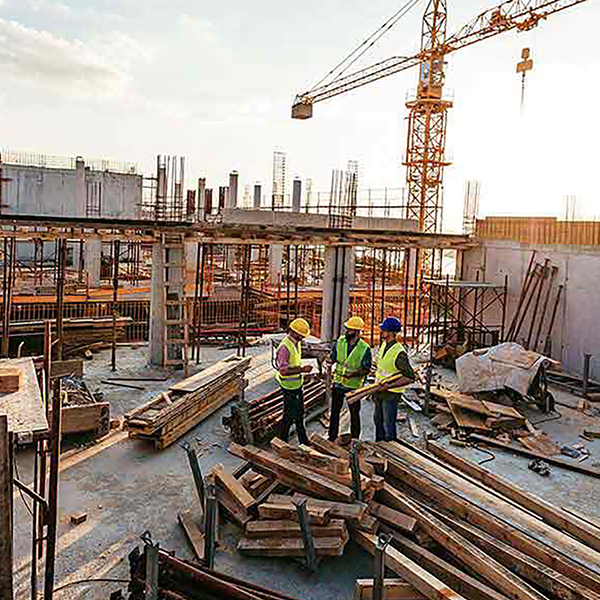 A trio of construction workers standing on a rooftop that's under construction.