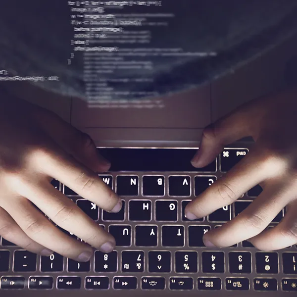 Concept of code with hands typing at a laptop computer in the background.