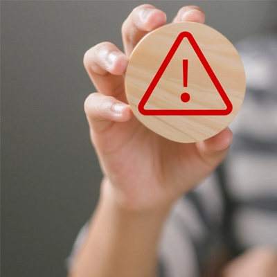woman's hands holding a circular wood with warning or caution sign