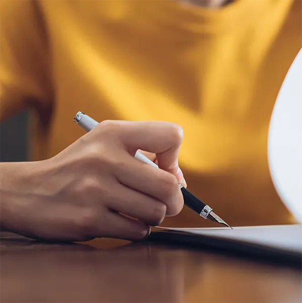 A close up of someone's hands as they're filling out paperwork.