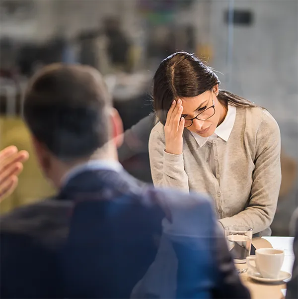 A professional woman in a meeting looking stressed.