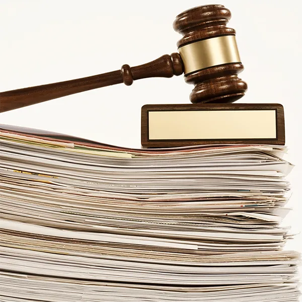 A gavel and sounding block rest on top of a stack of folders.