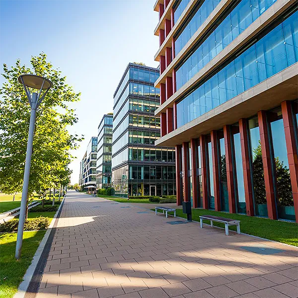A series of office buildings next to a green lawn and brick sidewalk.