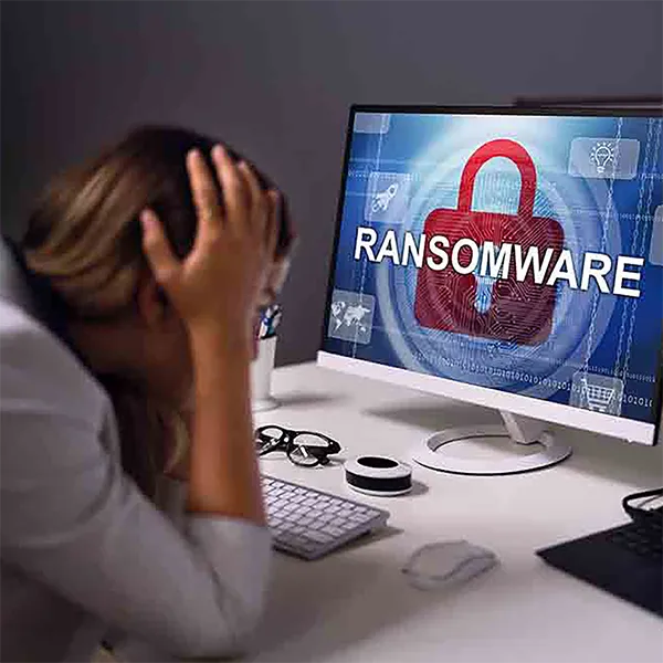 A person holding their head in their hands, staring at a computer screen that reads 'ransomware.'