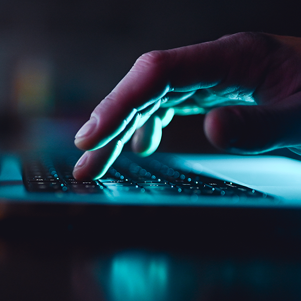 A hand typing at a laptop keyboard.