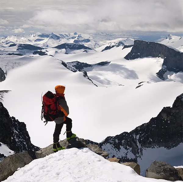 A hiker at the top of a snowy mountain range.