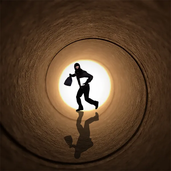 A person dressed as a thief running through a tunnel.