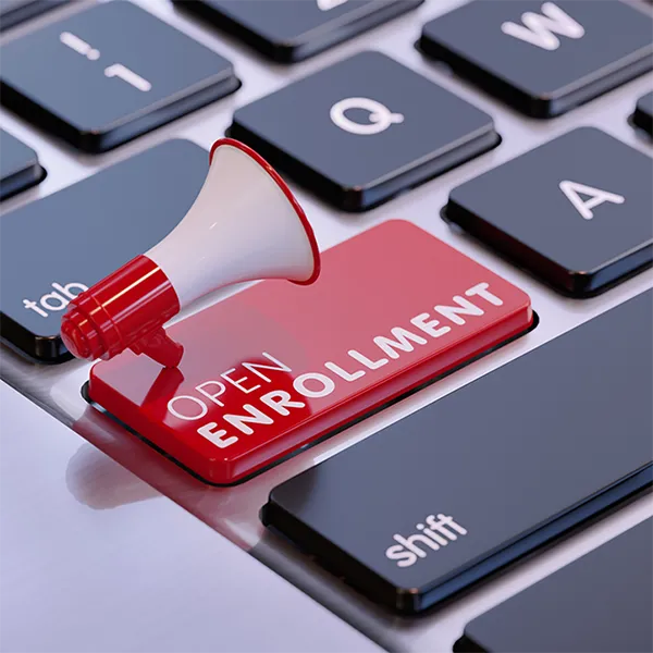 A keyboard with one bright red button reading 'Open Enrollment.' A tiny megaphone rests on top of the button.