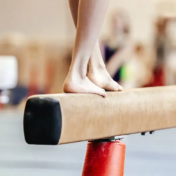 A gymnast standing on a balance beam.
