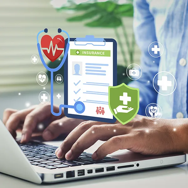 Someone typing on a laptop computer. An icon representing health insurance is in the foreground.