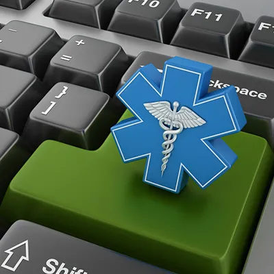 A close up image of a keyboard with a medical caduceus in a blue asterisk shape on the return key.