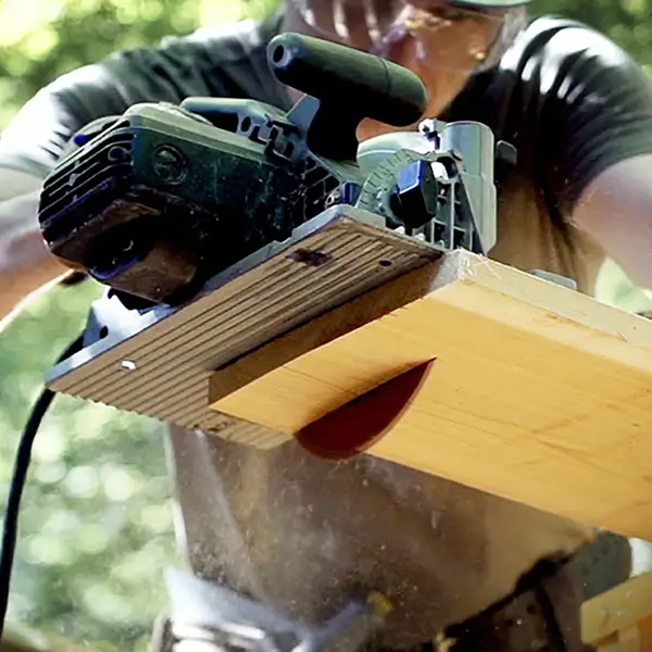 Someone cutting a wooden board with a circular saw.
