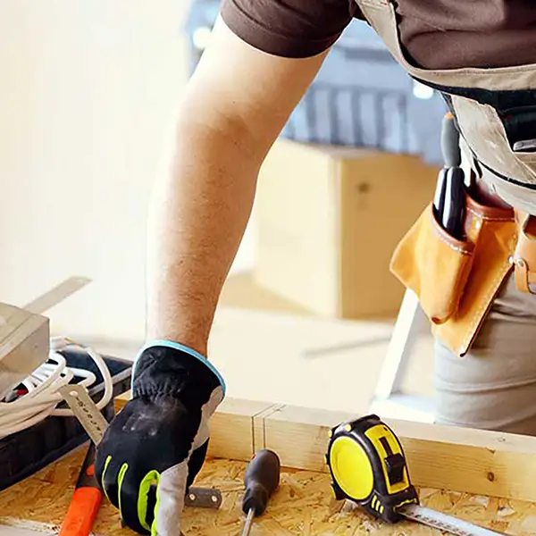 A contractor at a workbench surrounded by tools.