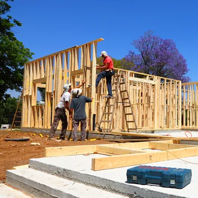 A construction site with wood framing being erected by construction workers.
