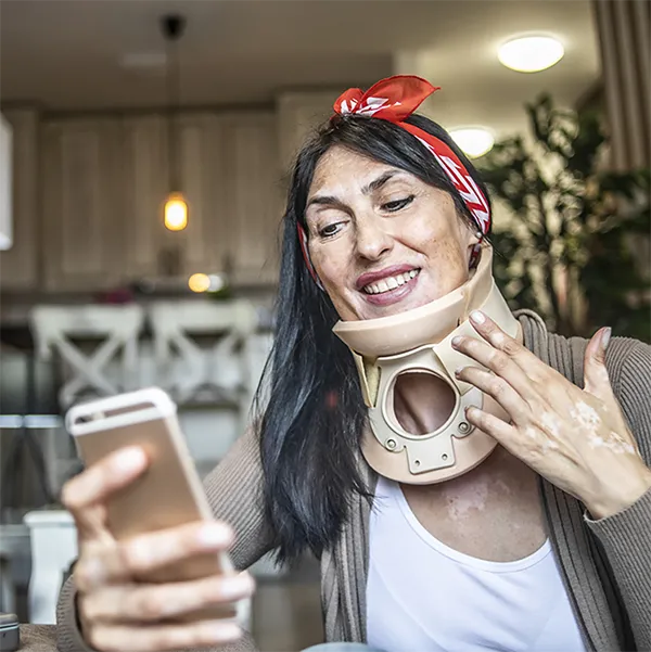 A woman in a neck brace using her cell phone.