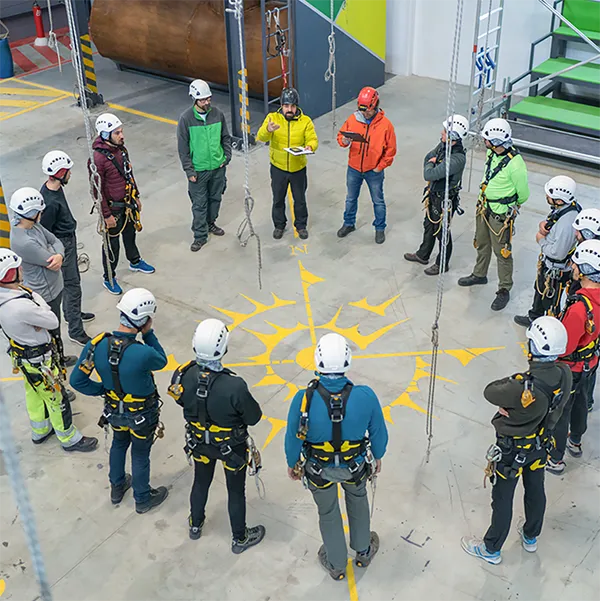 A circle of people wearing climbing gear and helmets.