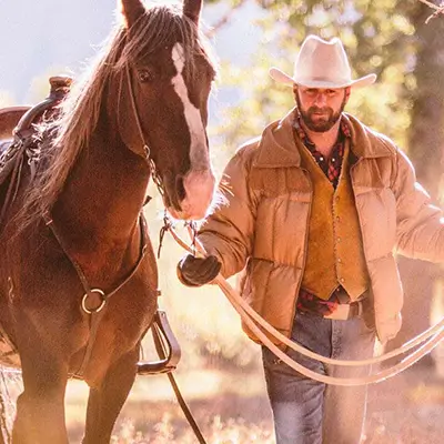 A horseback rider leading a horse by the reins.