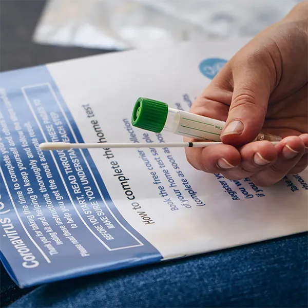 Someone holding a COVID testing looking at an instruction book.