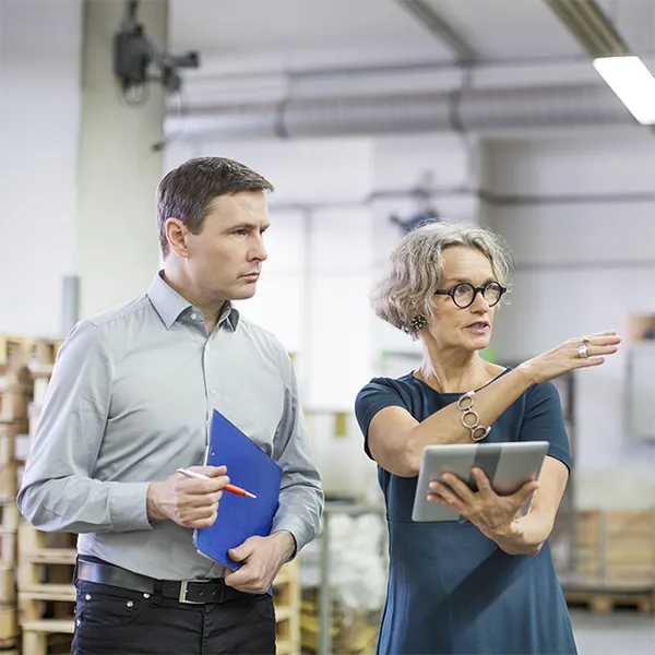 A person with a clipboard and a person with a tablet conduct a workplace inspection.