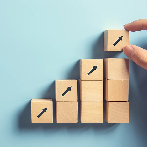 A hand stacking wooden blocks to mimic a bar graph.