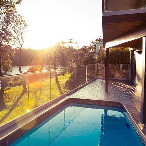 A home's patio and pool next to a green lawn.