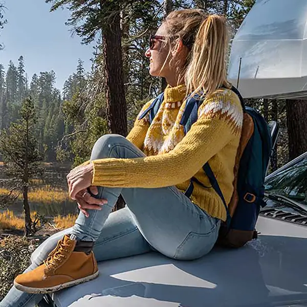 A woman sitting on the front hood of a camper van.