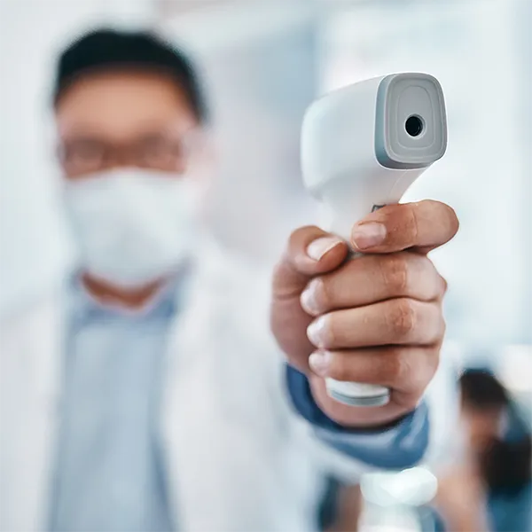 A medical professional wearing a mask takes a patient's temperature.