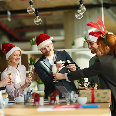 A group of office workers wearing holiday garb and toasting with champagne.