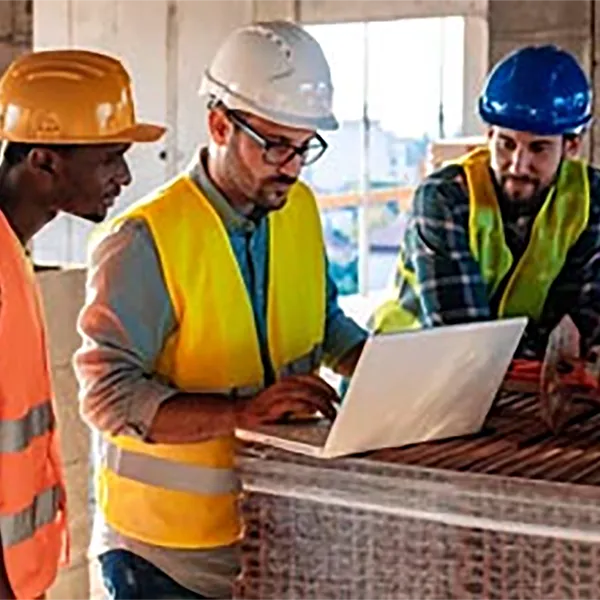 Three contractors looking at a laptop computer.