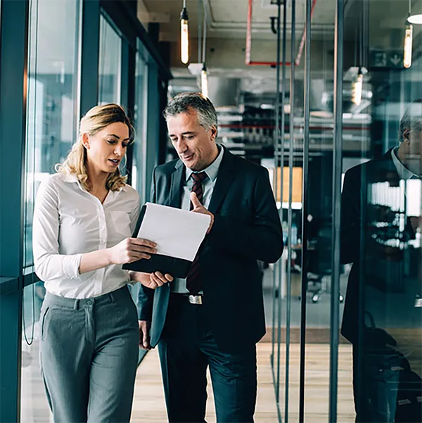 Two professionals reviewing information on a clipboard.