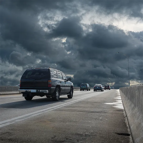 Cars on the highway with dark storm clouds in the background.