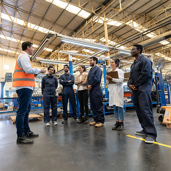 A group of workers in an industrial setting in a meeting.