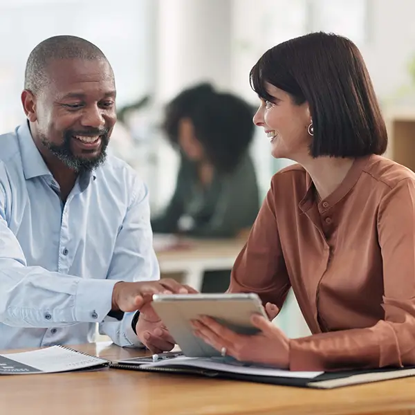 Two professionals discussing business insurance while looking at a tablet.