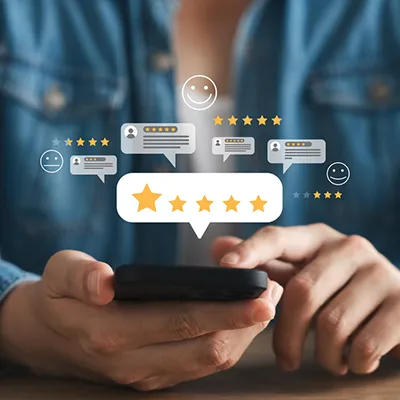 A person holding a phone in their hands with chat bubbles and emojis floating above the phone.