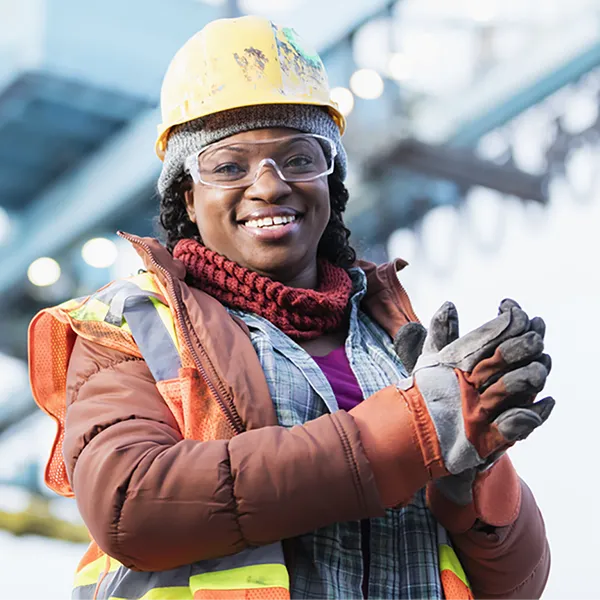 A construction worker dressed for winter weather wearing a hard hat and gloves.