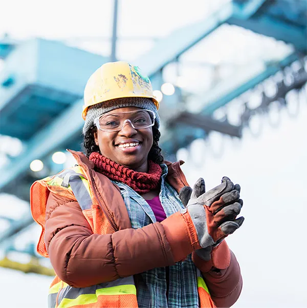 A construction worker dressed for winter weather wearing a hard hat and gloves.