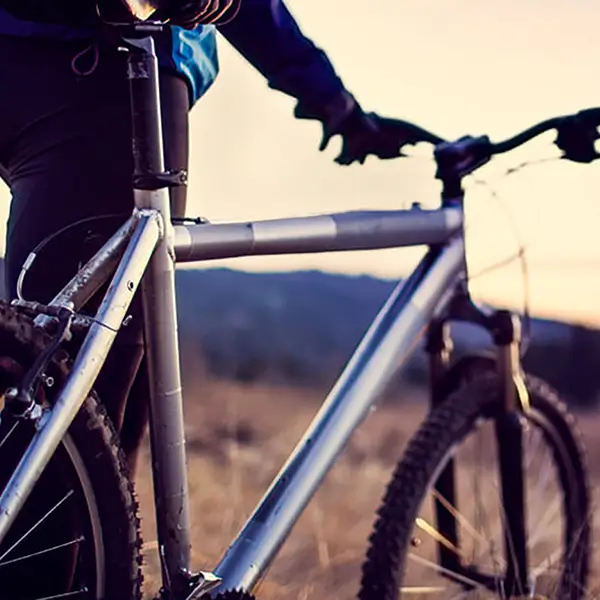 A person standing with their mountain bike.